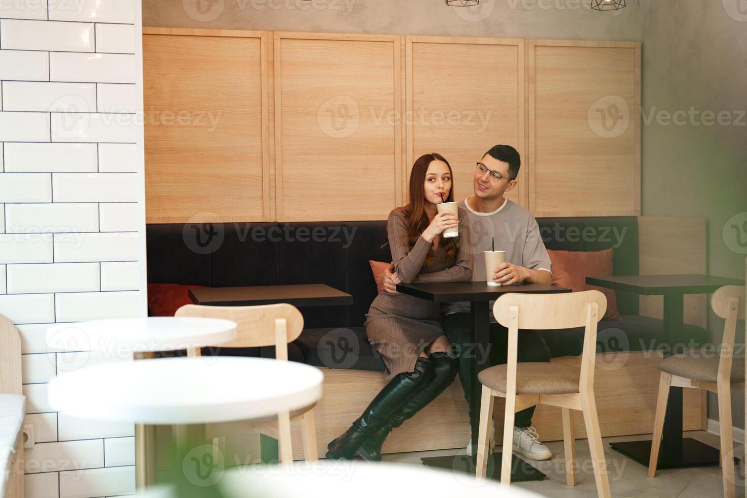 Couple enjoys drinks and cozy conversation in modern cafe setting during afternoon hours photo