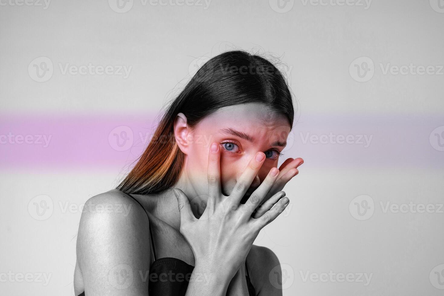 Portrait of a woman expressing emotion with hands covering her face in a minimalist setting during daylight photo