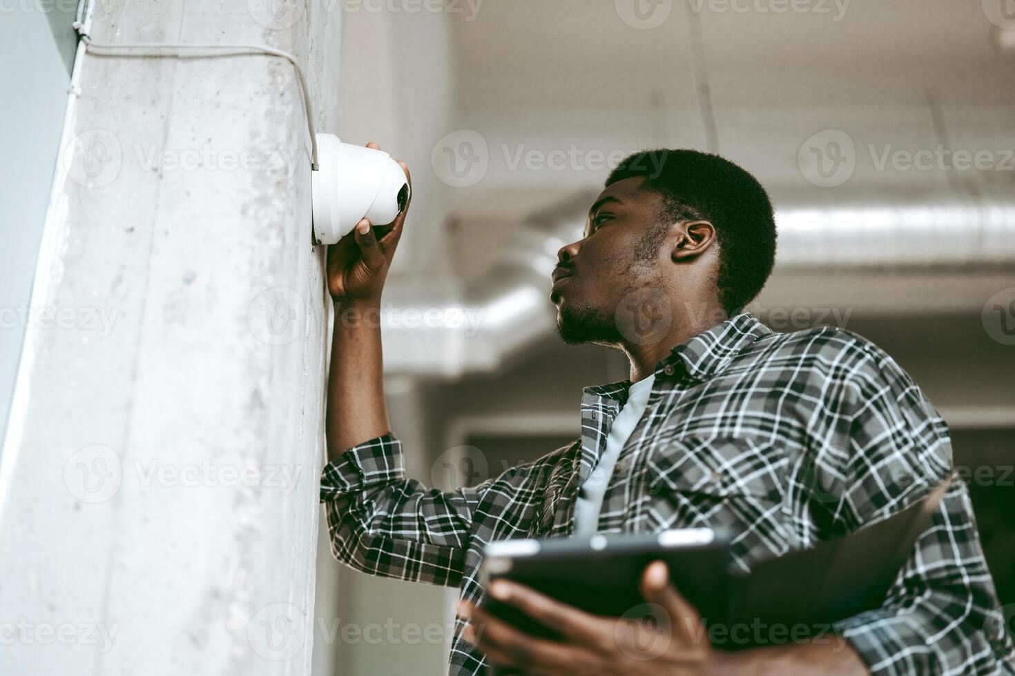 Technician installs security camera in modern office building during daylight hours photo