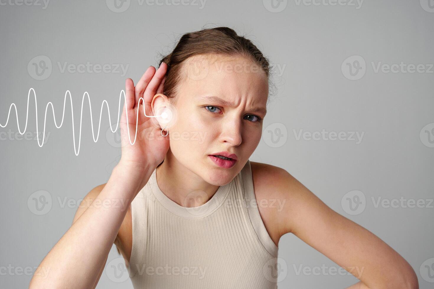 Woman listening carefully to a sound wave, showing concentration in a neutral-toned space photo