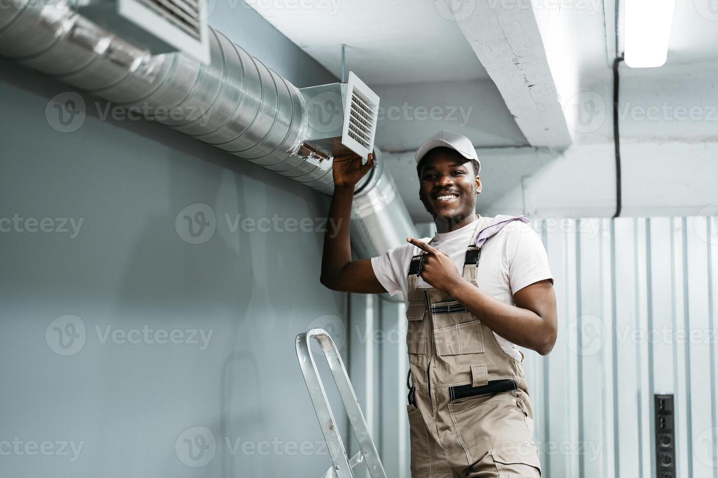 Skilled worker proudly points at air vent in modern workshop during installation process photo