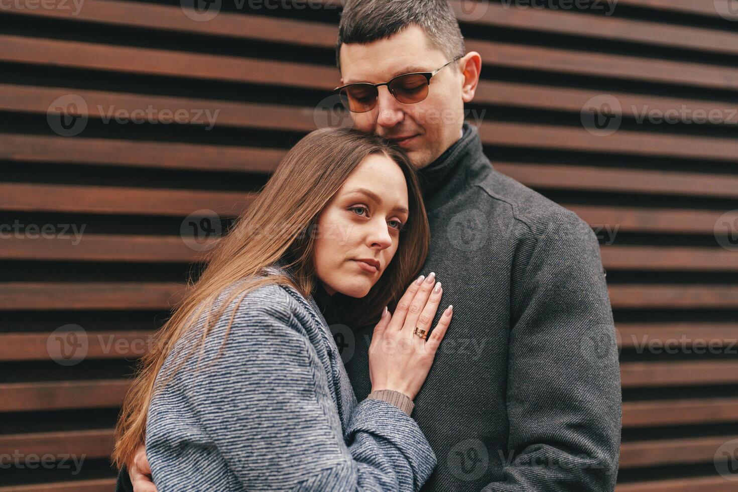 Couple sharing a warm embrace against a wooden backdrop on a cool day in a city setting photo