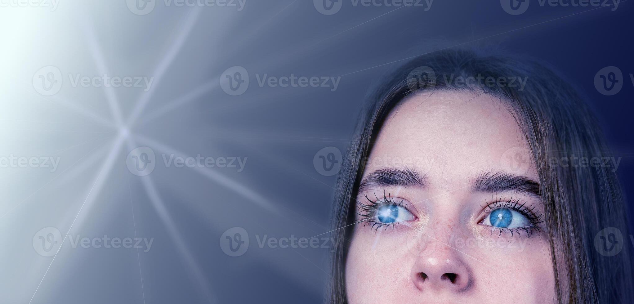 Person with blue eyes gazing thoughtfully into a soft light against a dark background photo