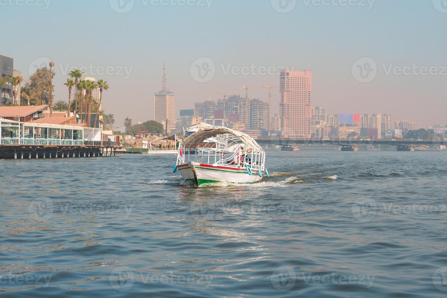 Boats navigate the Nile River with Cairo's skyline in the background during a clear day photo