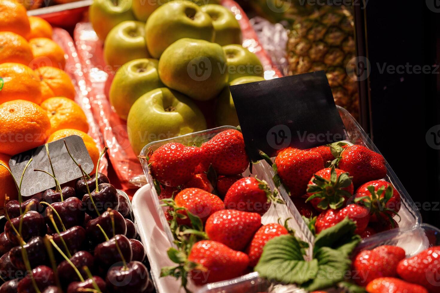 Colorful fruit display showcasing fresh strawberries, cherries, green apples, and vibrant oranges at a local market during early afternoon hours photo