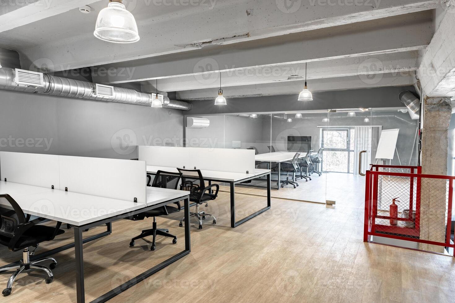 Modern coworking space with desks and chairs in a well-lit office environment on a bright day photo