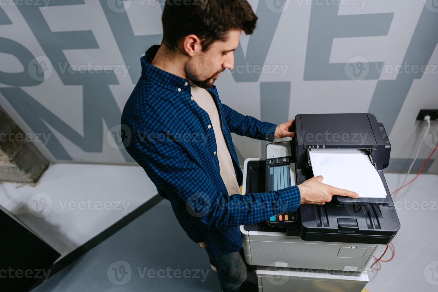 Office worker using a multifunction printer to print documents in a modern workspace photo