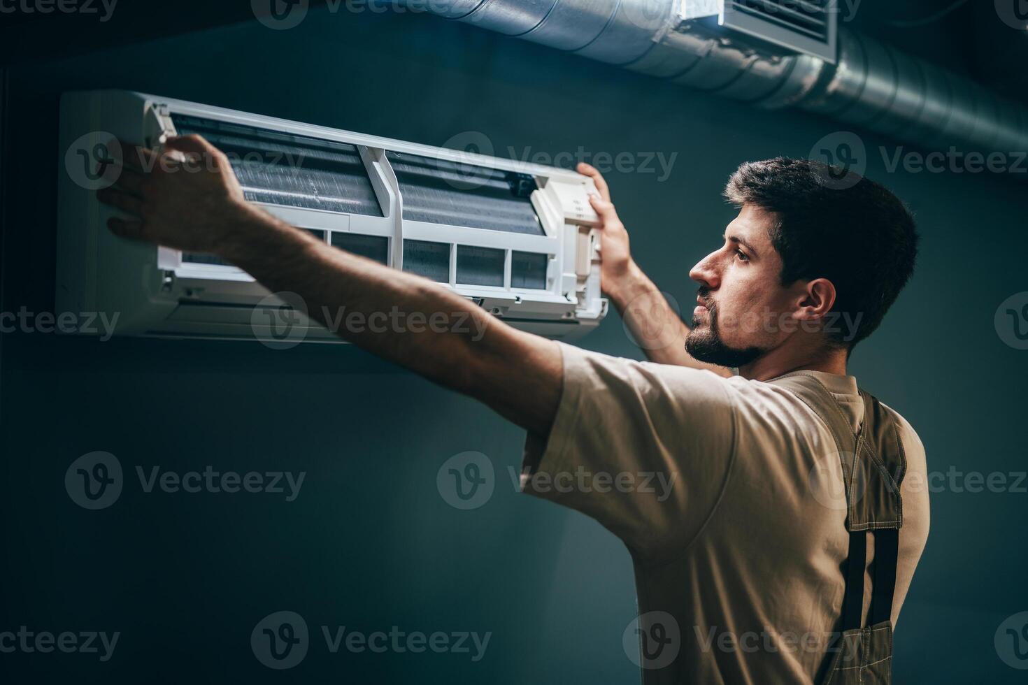 Technician installs air conditioning unit in residential space during daylight hours photo