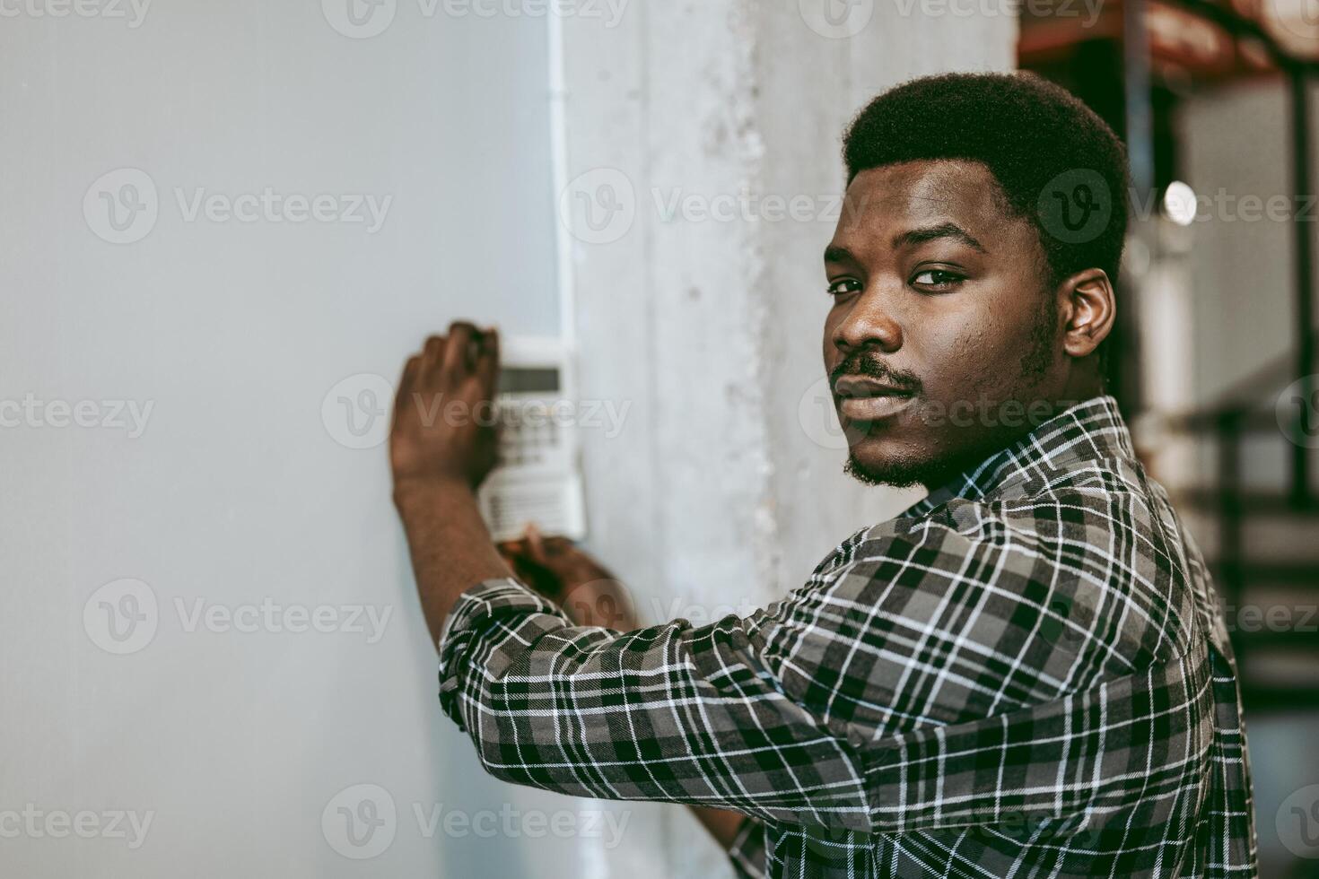 Young man adjusting controls on a device in an industrial space during the day photo
