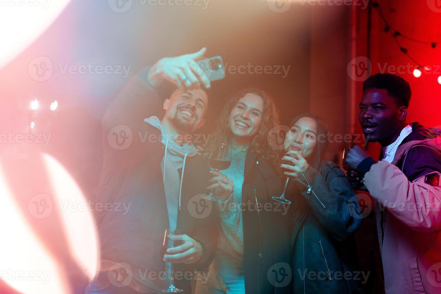 Friends enjoying a night out, taking selfies, and celebrating a special occasion at a lively venue with colorful lights photo