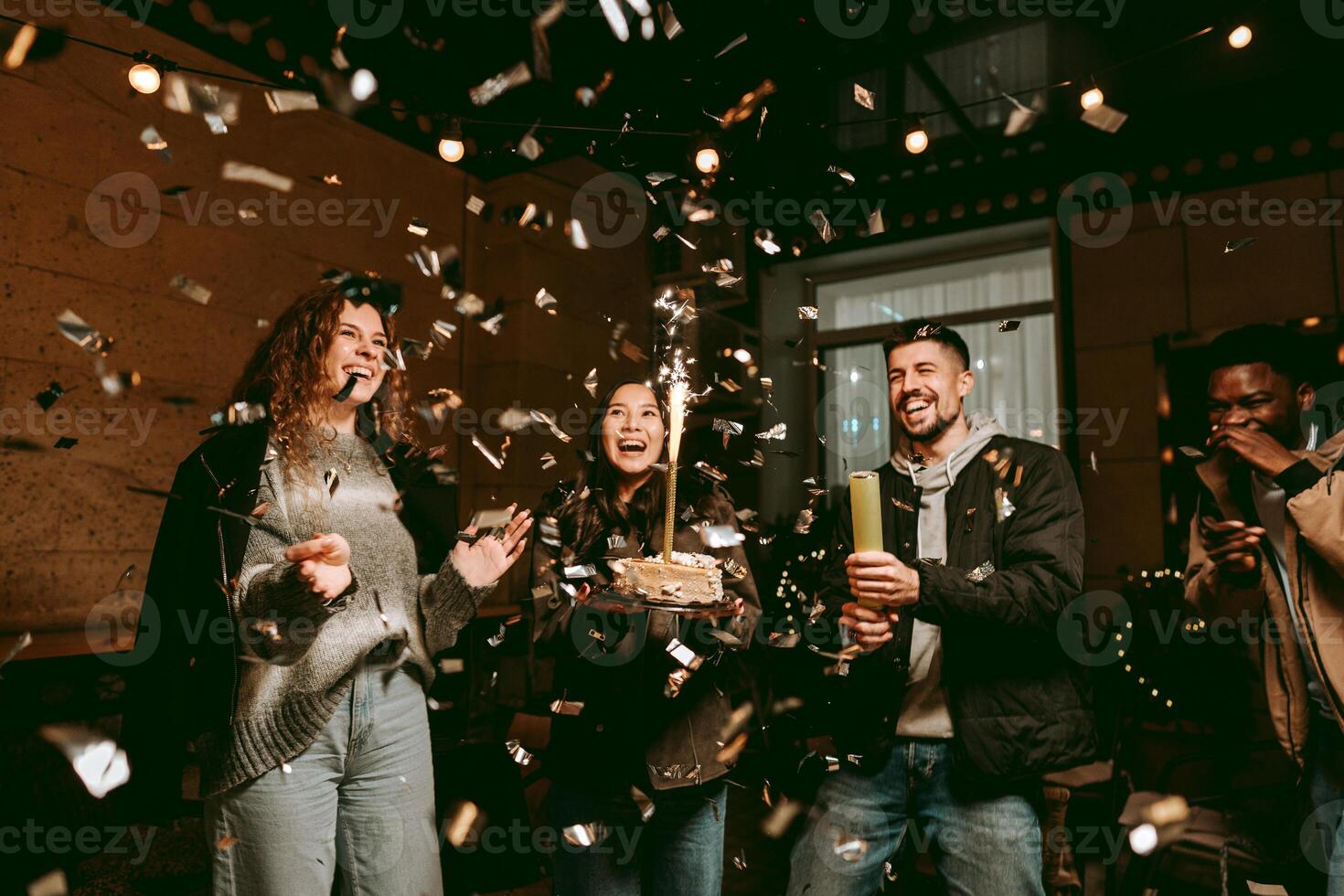 Friends celebrate with cake and confetti during a joyful gathering at a cozy venue in the evening photo