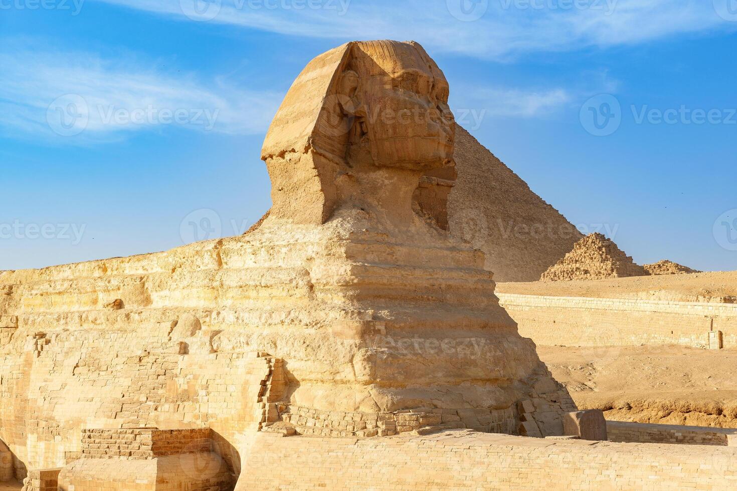 Majestic Sphinx stands guard near the Great Pyramid in Giza under a clear blue sky photo