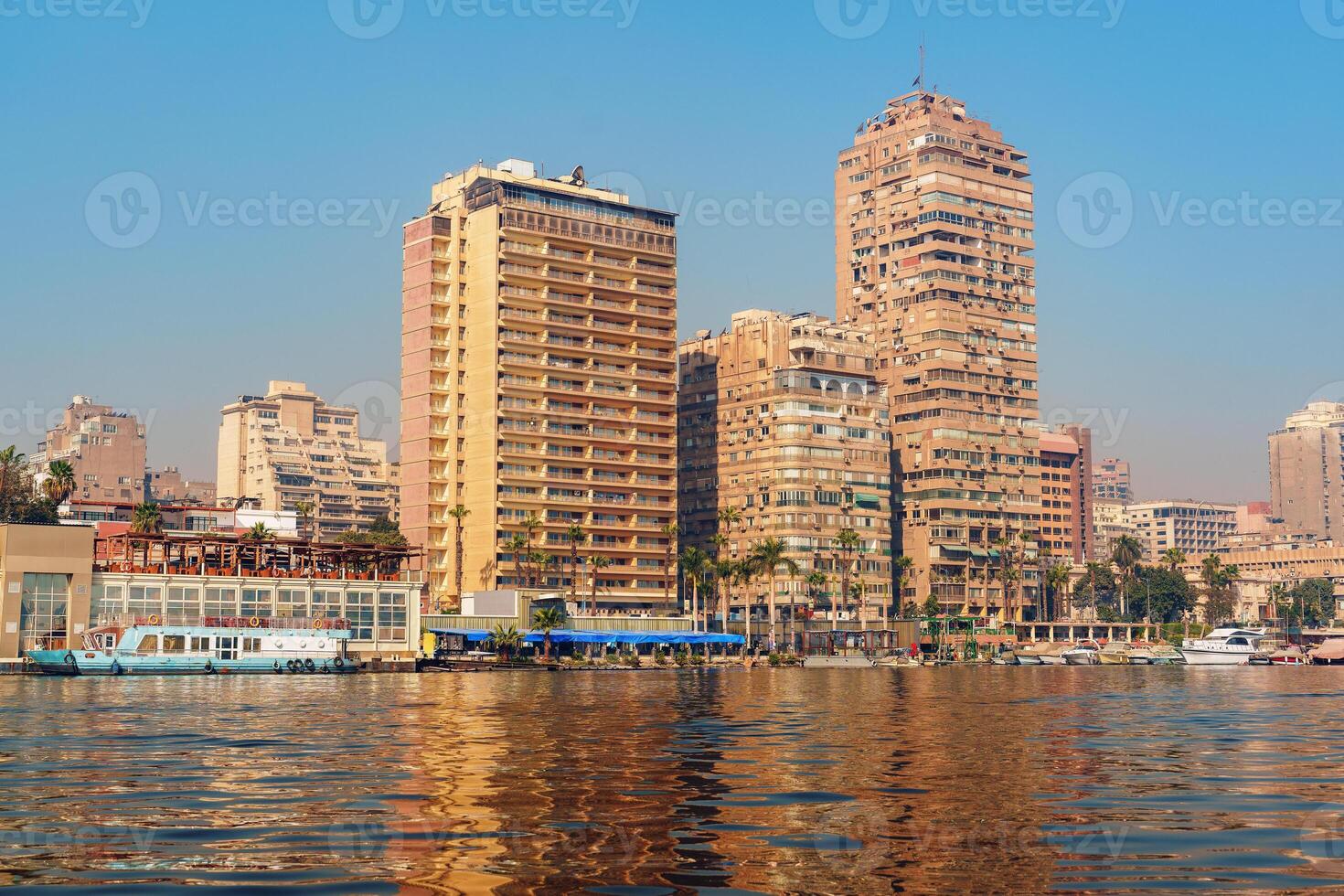Vibrant waterfront view of Cairo with modern buildings and reflections during a sunny day photo