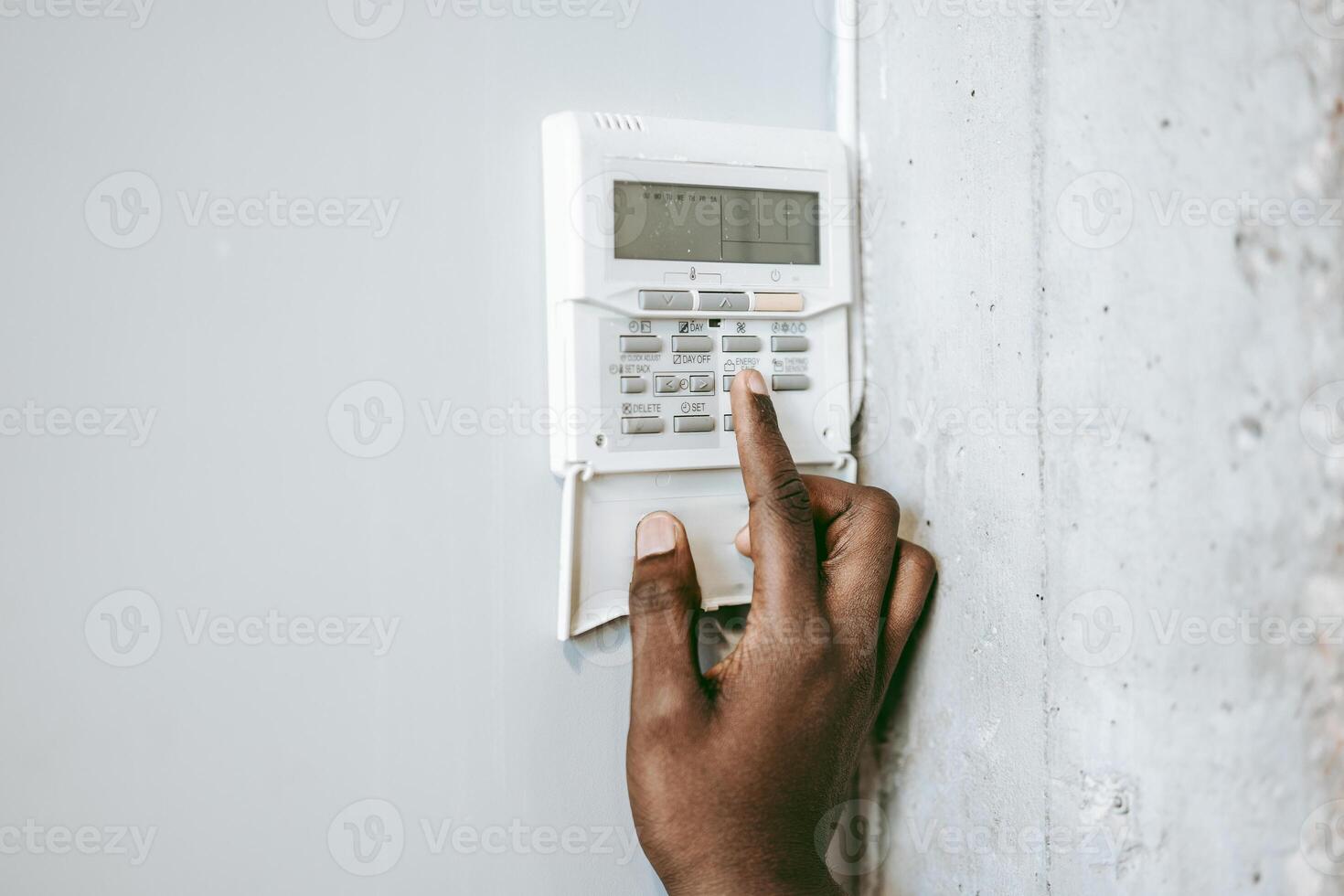 Person interacting with a security panel on a wall in a modern setting during daytime photo