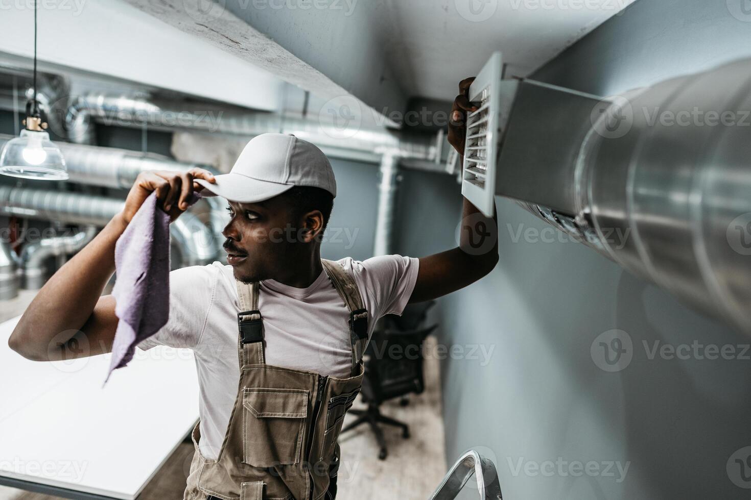 Maintenance worker performs air vent cleaning in modern office setting to ensure optimal air quality and comfort for employees during work hours photo