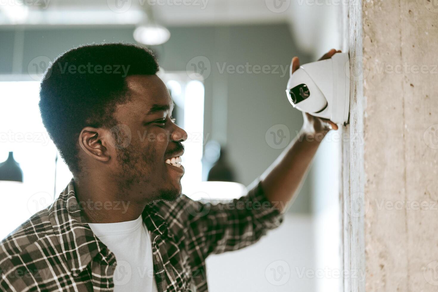 Man installs security camera indoors in modern workspace during daylight hours photo