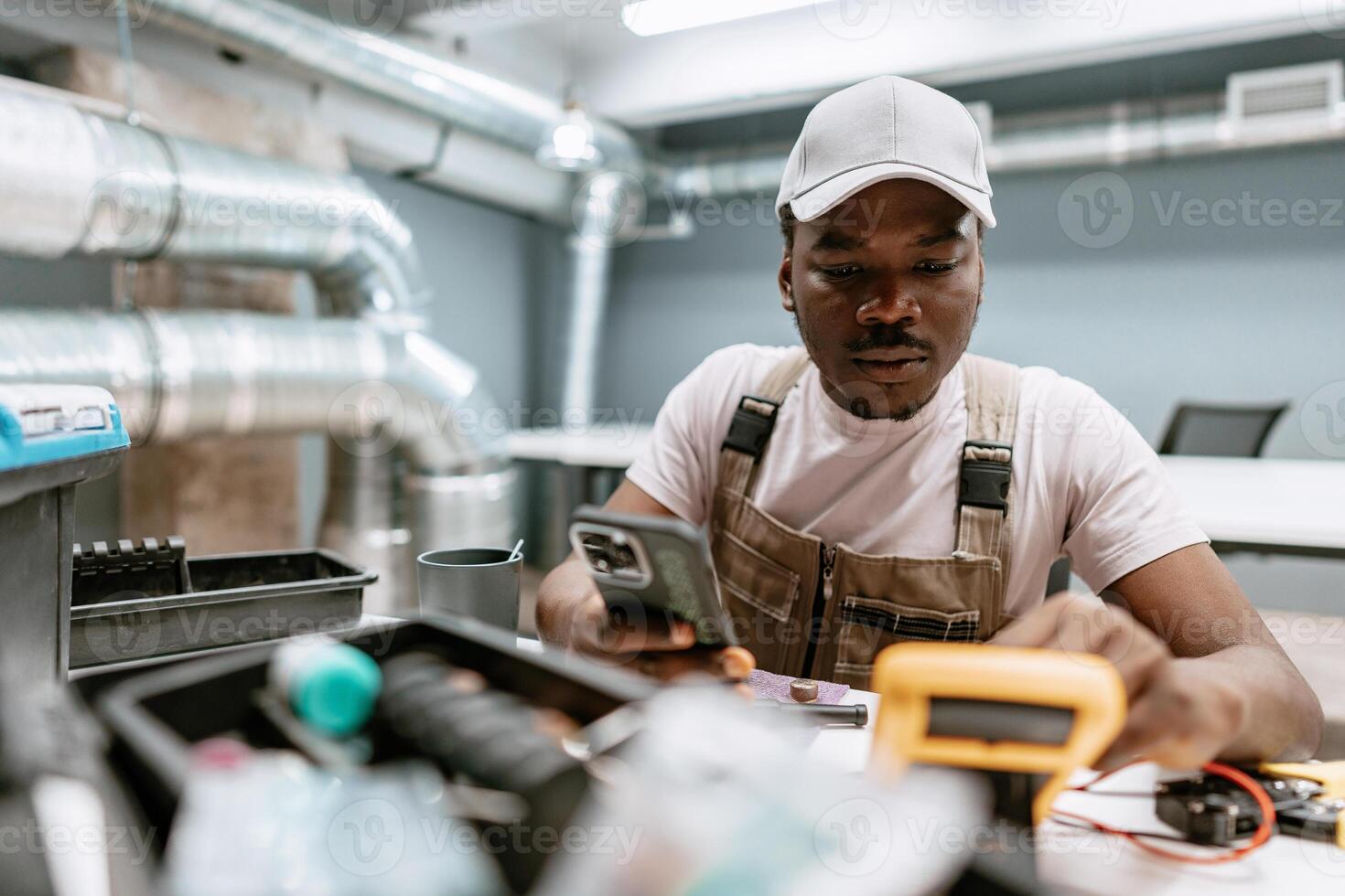 Technician conducting electrical tests with tools and smartphone in modern workshop environment photo