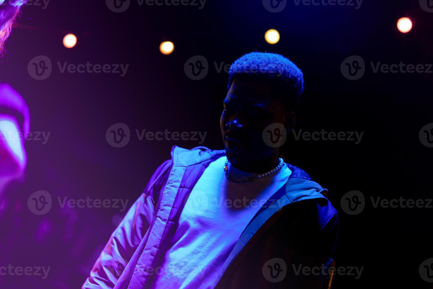Nighttime event featuring a young man in stylish attire under colorful lighting photo