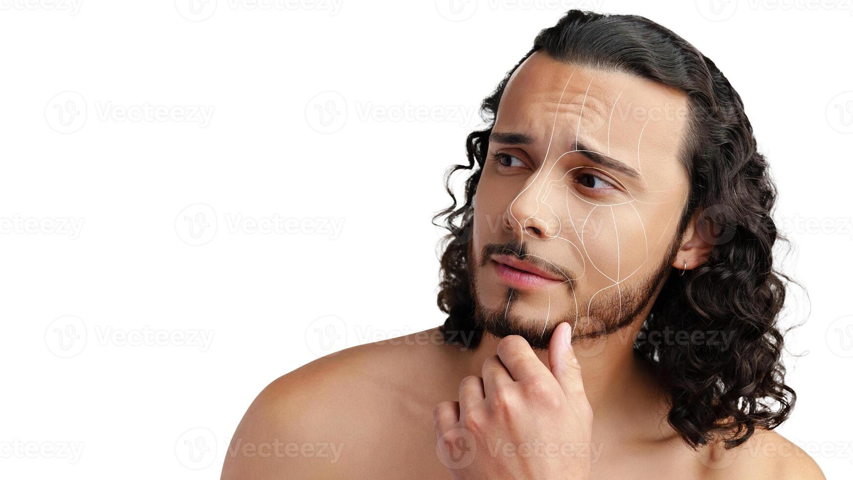 Man with curly hair thoughtfully examines his skin while revealing facial lines and texture in a neutral setting photo