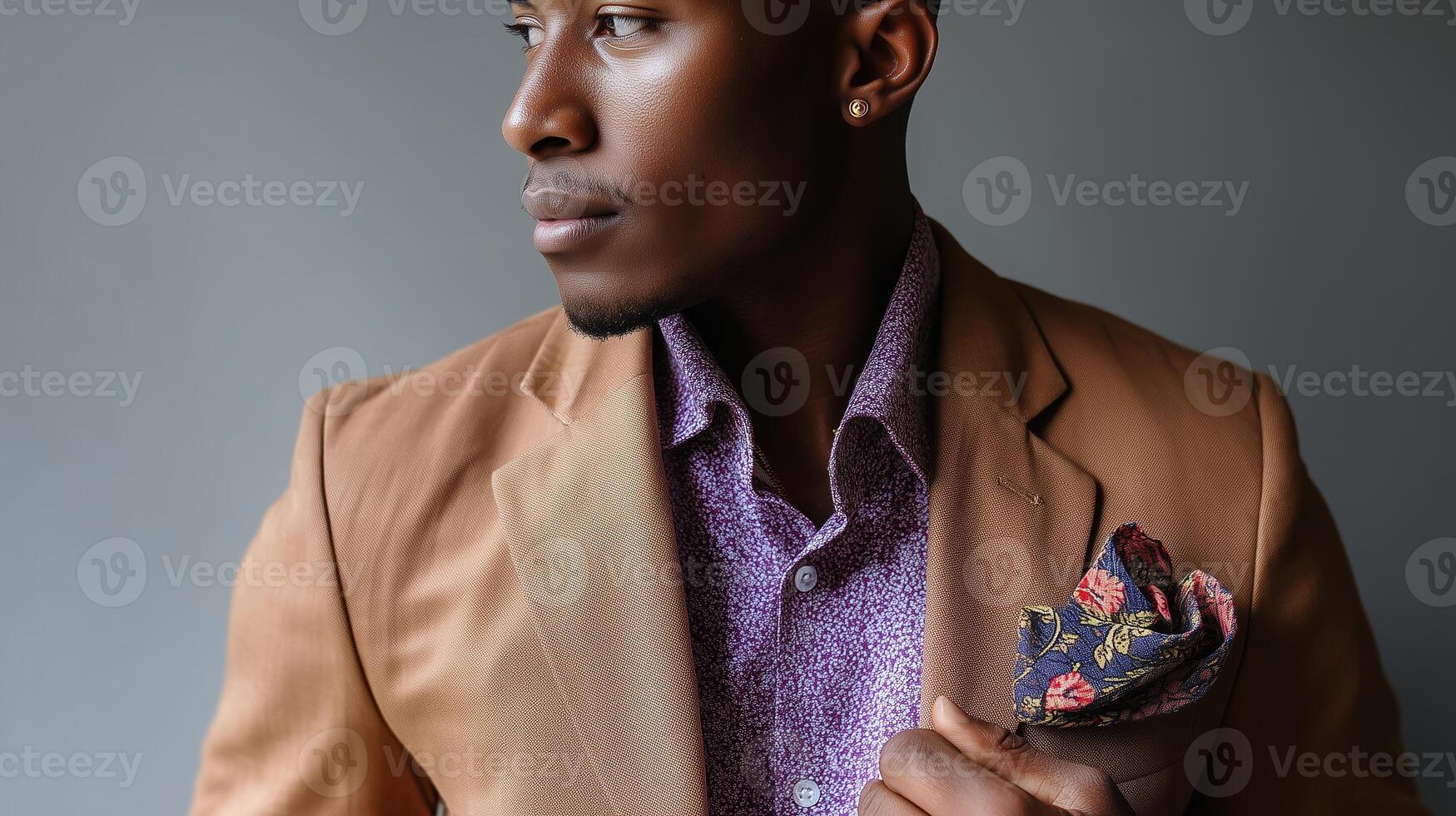 Man in a stylish brown suit poses confidently against a gray background, showcasing elegance and modern fashion in a studio setting photo