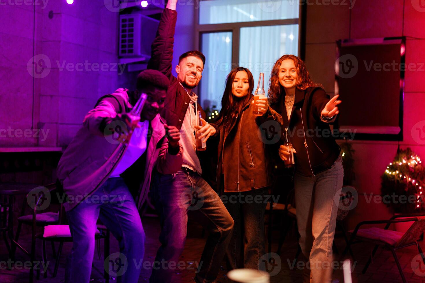 Friends celebrating joyfully at a vibrant nighttime gathering with drinks in a festive setting photo