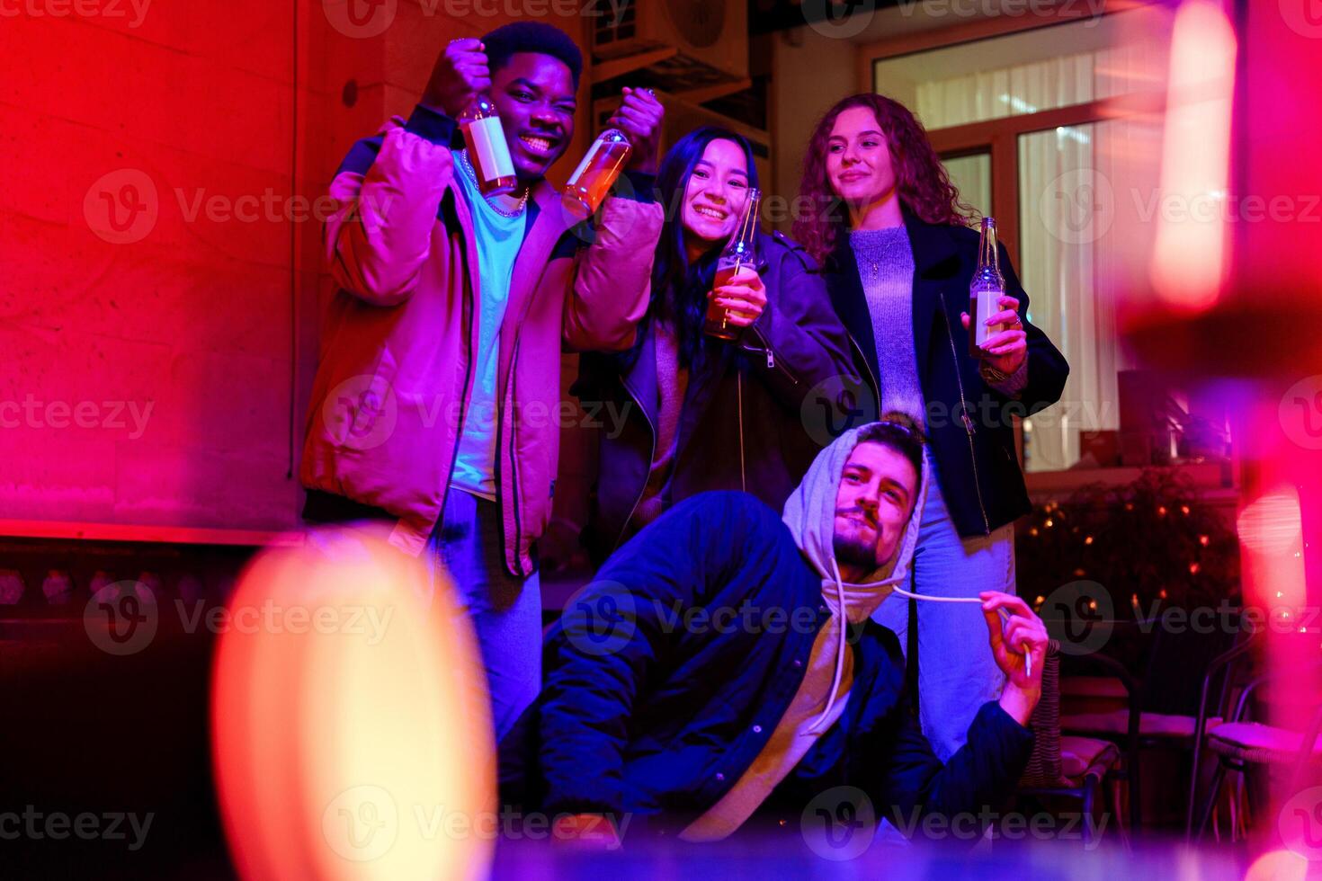 Friends celebrate with drinks in a lively indoor setting during a colorful evening gathering photo