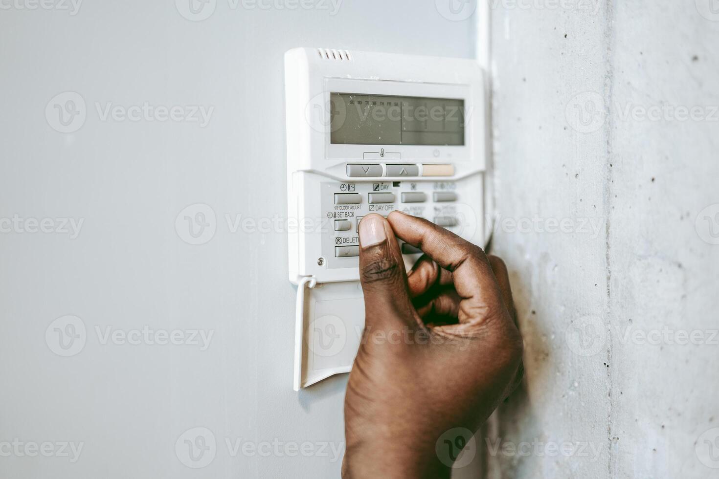 Hand adjusting security system panel against a concrete wall in a modern indoor setting photo