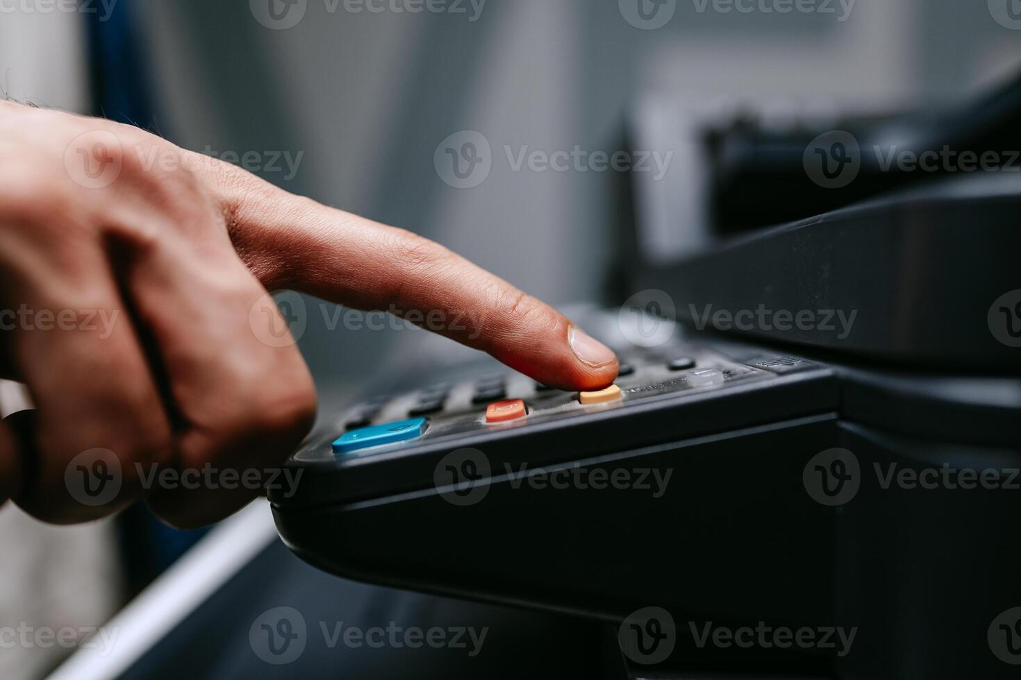Person pressing buttons on office equipment in a busy workspace during the day photo