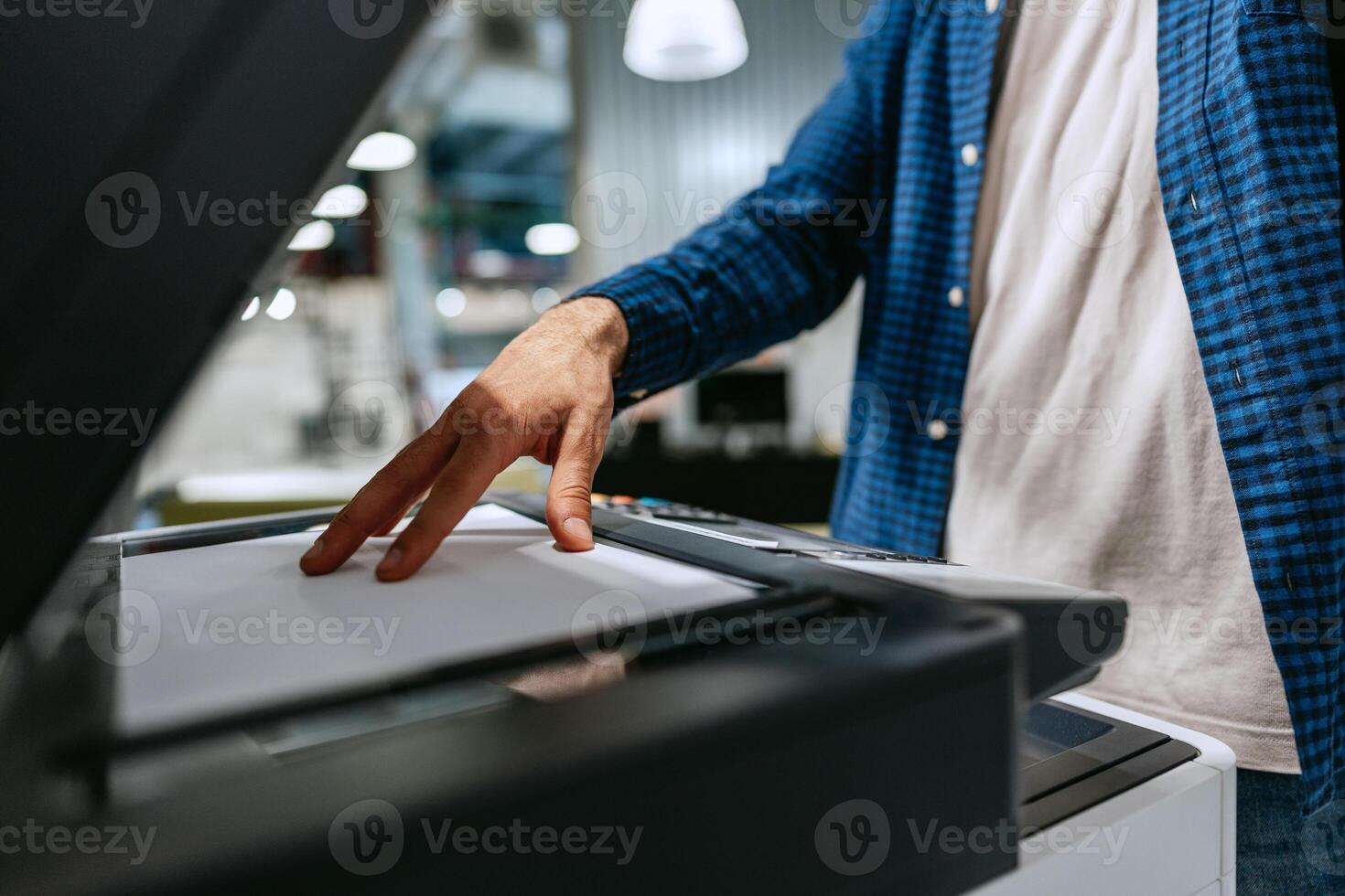 Person operating a printer to copy documents in a modern office environment photo