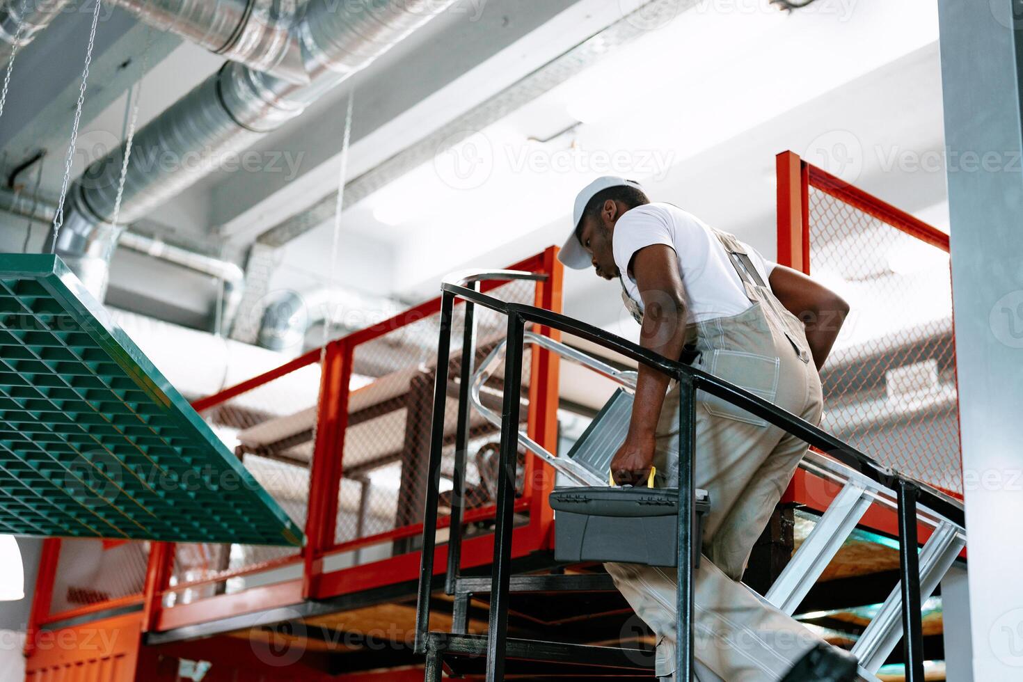 Worker ascending stairs with toolbox in modern industrial workspace during daytime hours photo