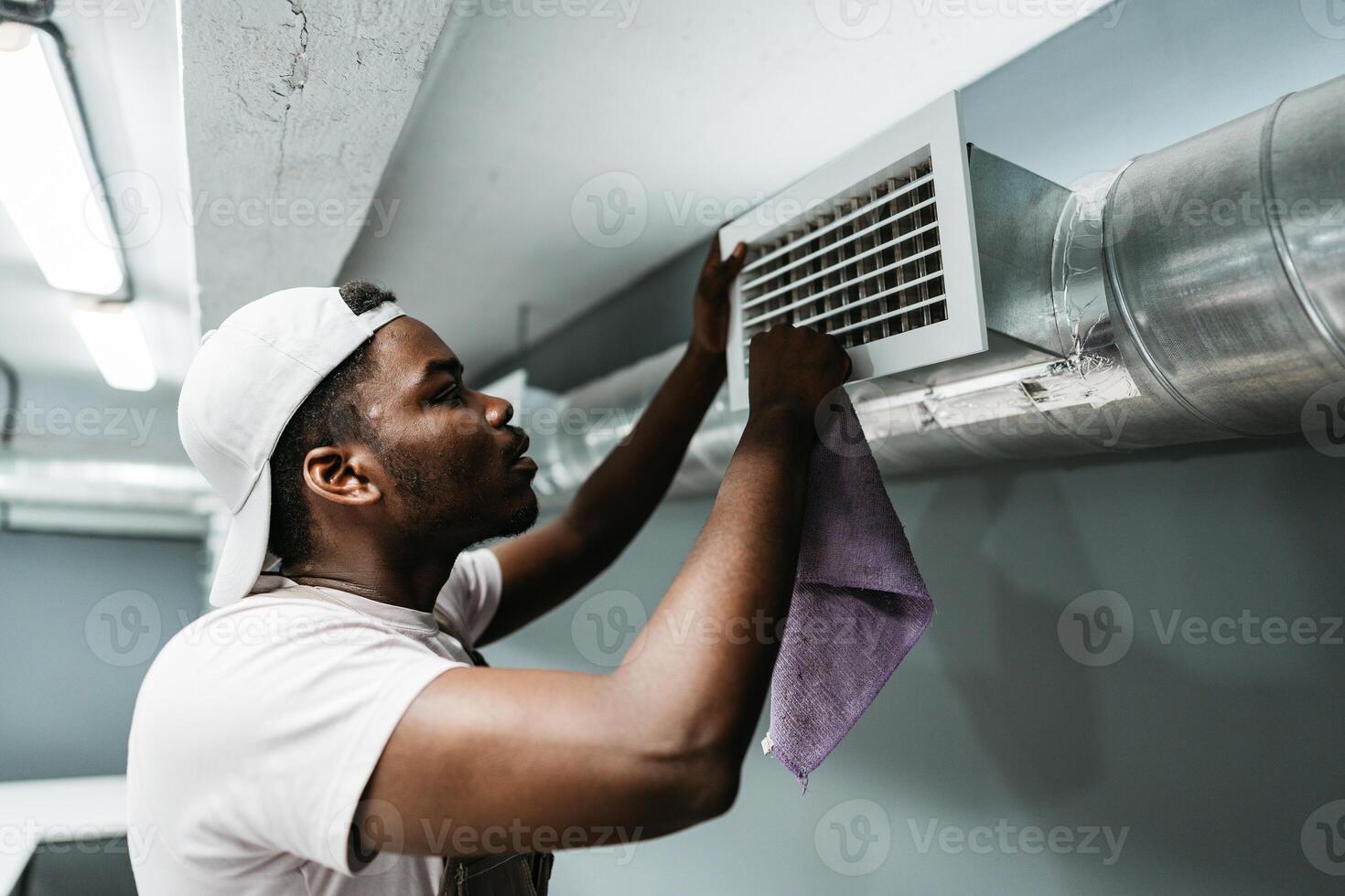 Man cleaning air vent in basement space during daylight hours for better air quality and system maintenance photo