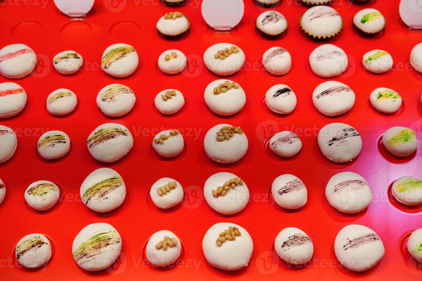 Colorful macarons arranged neatly on a bright red display reflecting an artful pastry shop environment photo