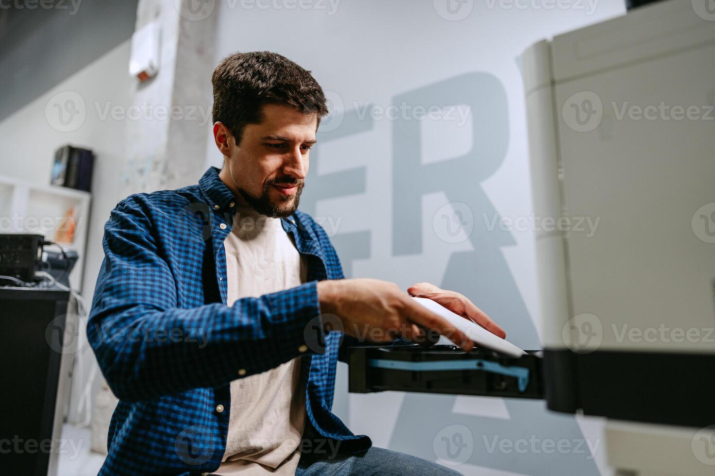 Man working diligently on printer equipment in modern office space during daytime photo
