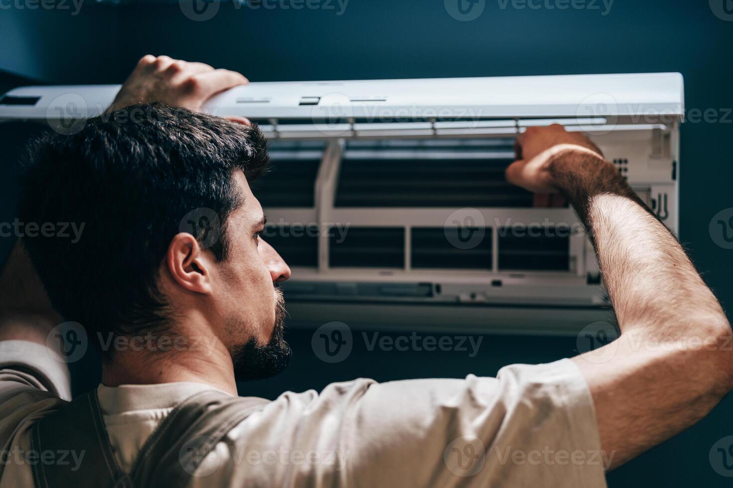 Technician performs maintenance on wall-mounted air conditioning unit in a modern room photo