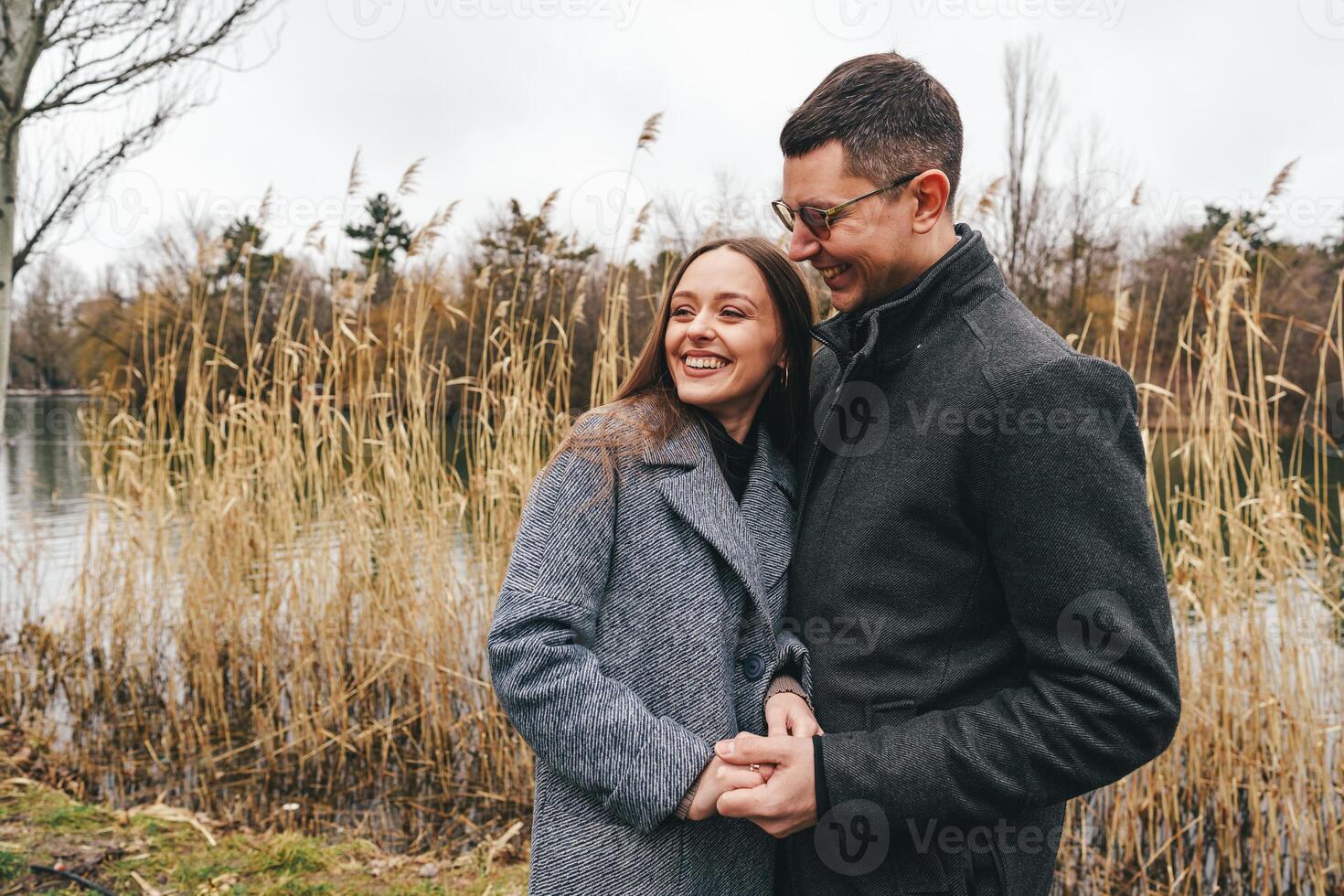 Couple enjoys a romantic moment by the lakeside during a cloudy day in autumn photo