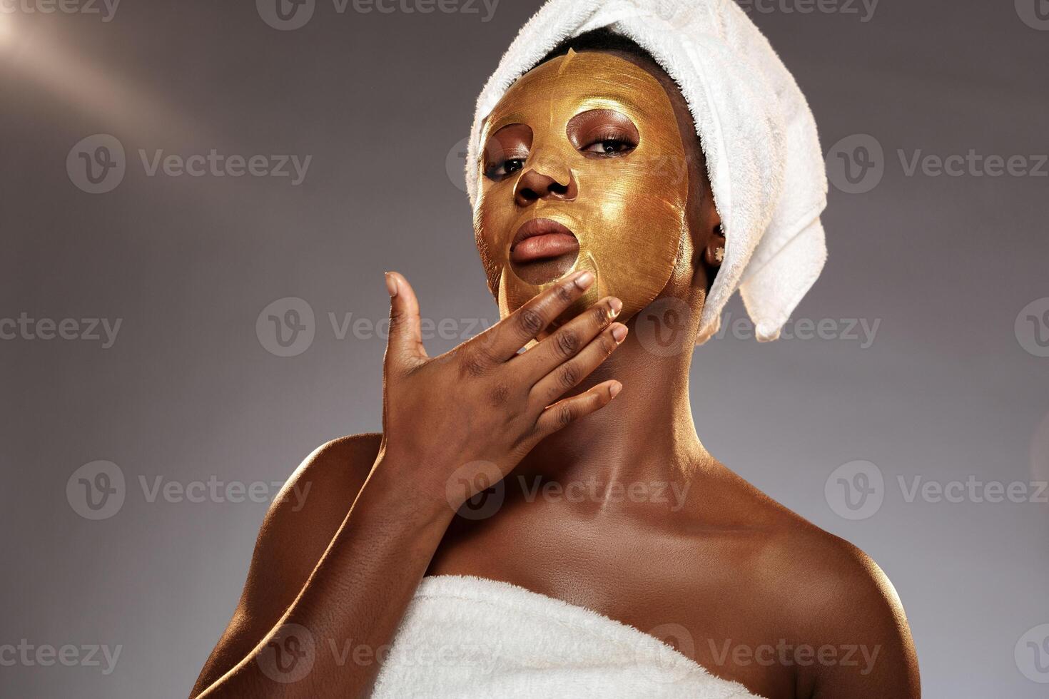 Woman applying gold facial mask at home for skincare routine during evening hours photo
