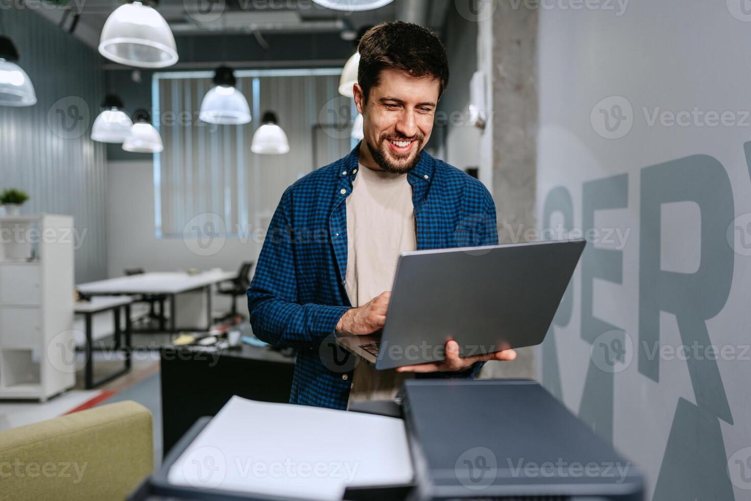 Man working on laptop in modern office space during daytime photo