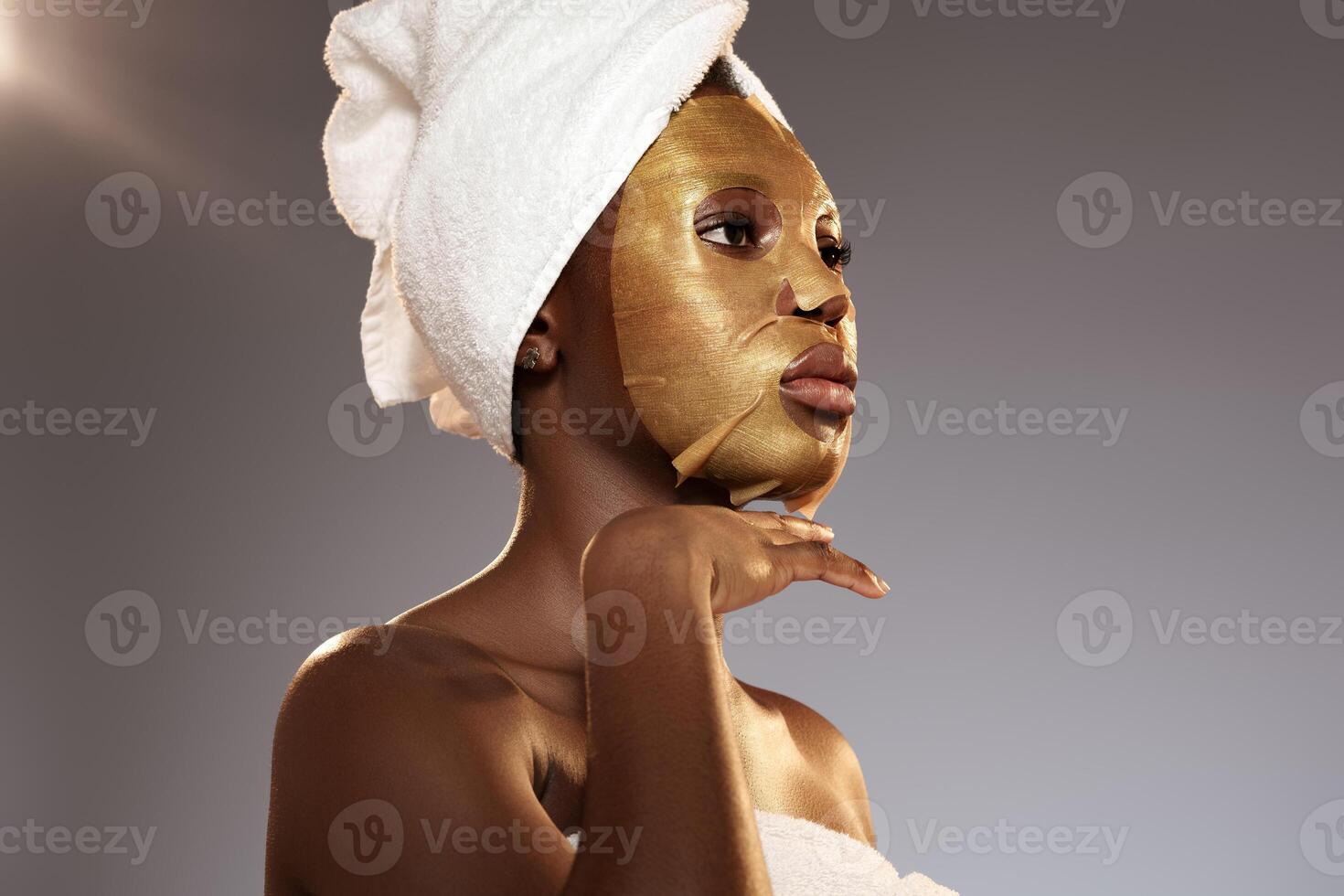 Woman applying gold facial mask during skincare routine in a calming environment photo