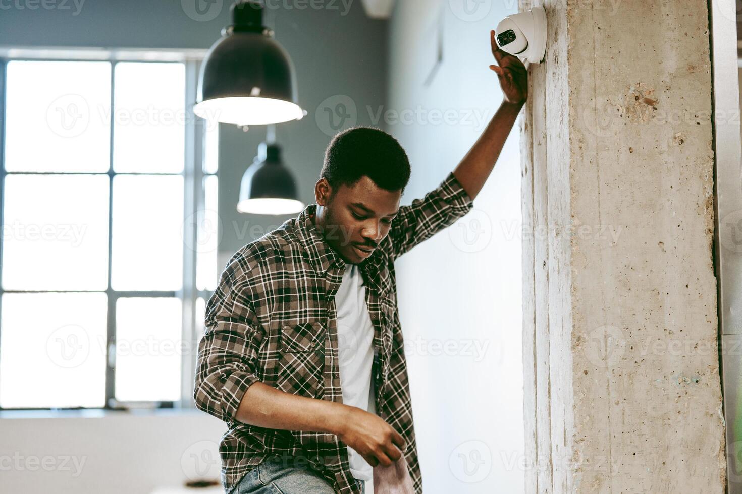 Young man inspecting a security camera in a modern workspace during the day photo