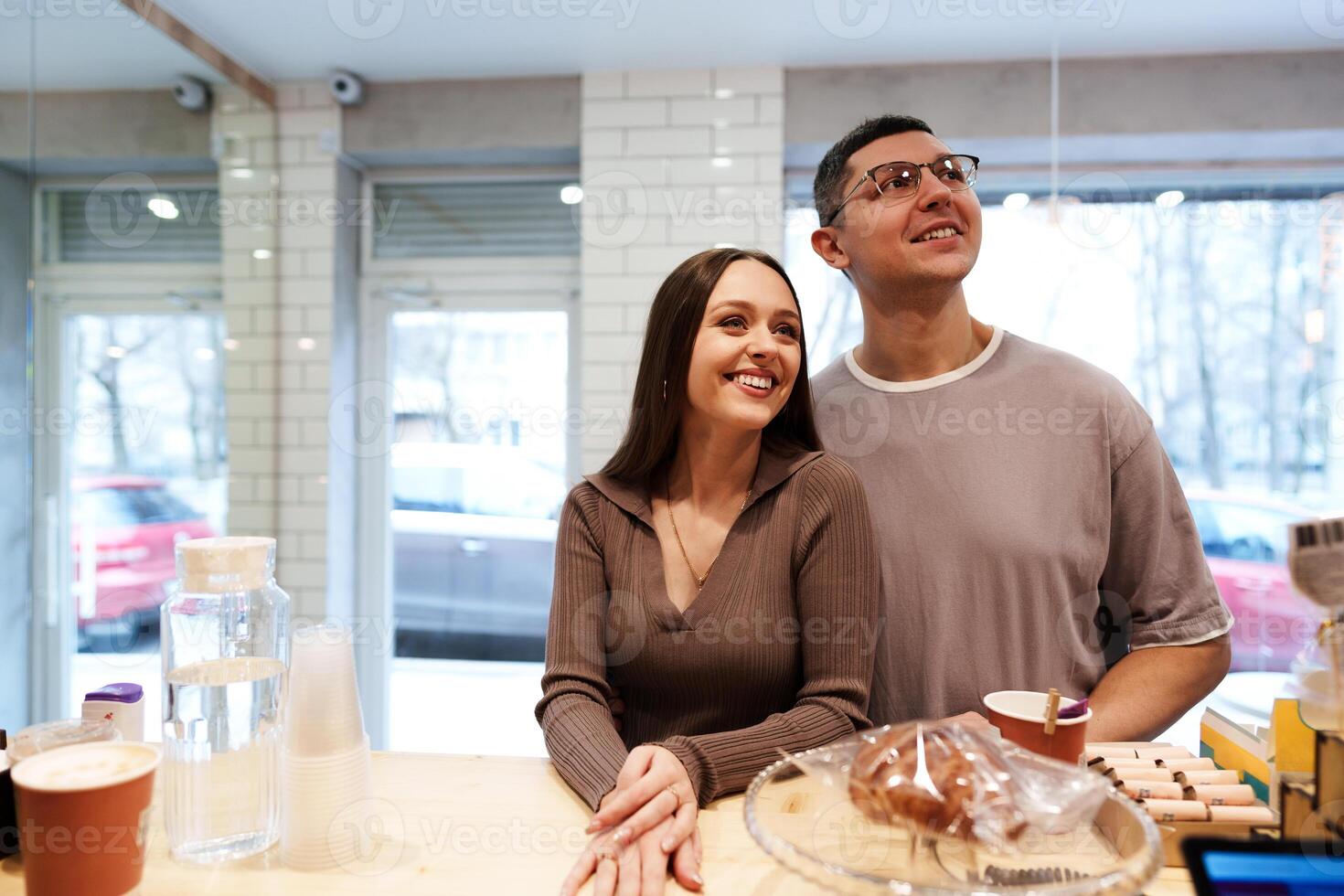 Couple enjoying a cozy moment at a cafe while sipping coffee and smiling at each other during a sunny afternoon photo