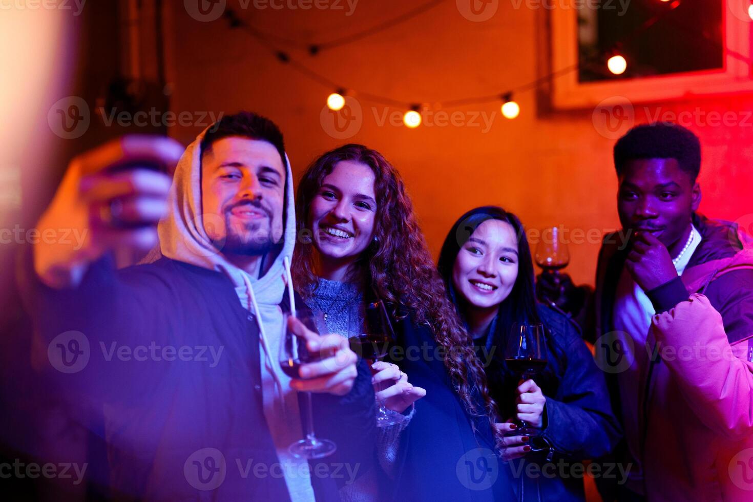 Friends enjoying a joyful evening with glasses raised in celebration at a vibrant outdoor gathering during nighttime photo