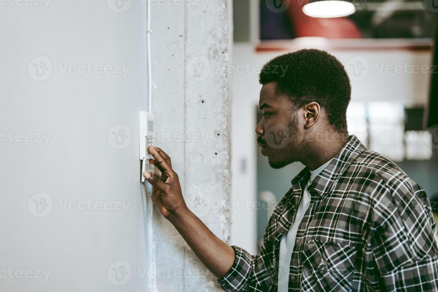 Man adjusting thermostat in modern office space during daytime while focused on energy efficiency photo