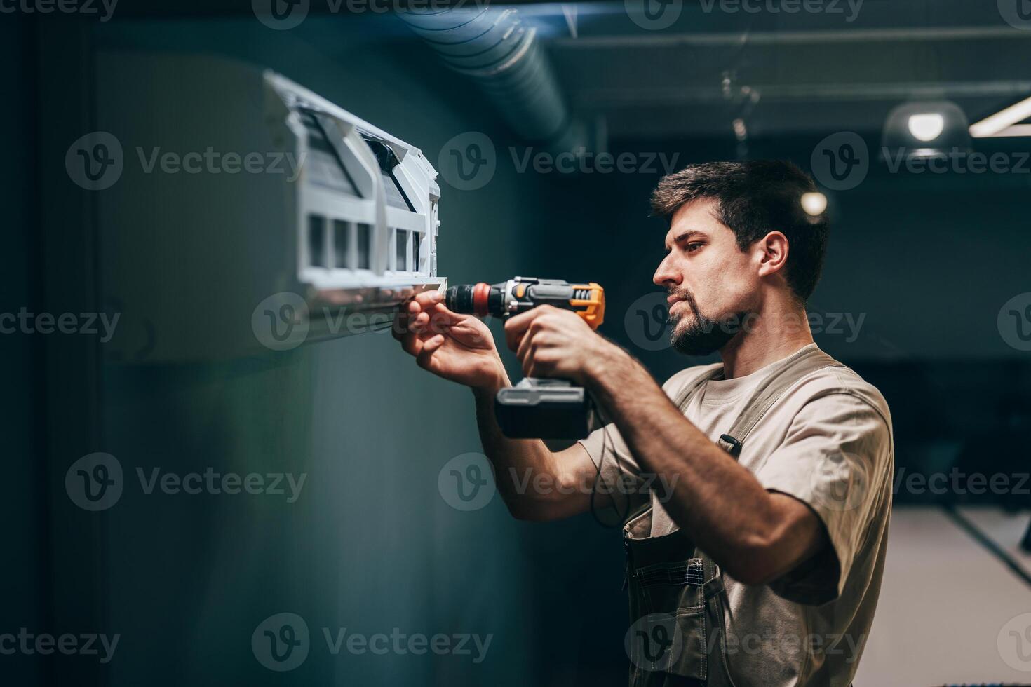 Man installs wall-mounted shelf in a modern indoor space using a power drill photo