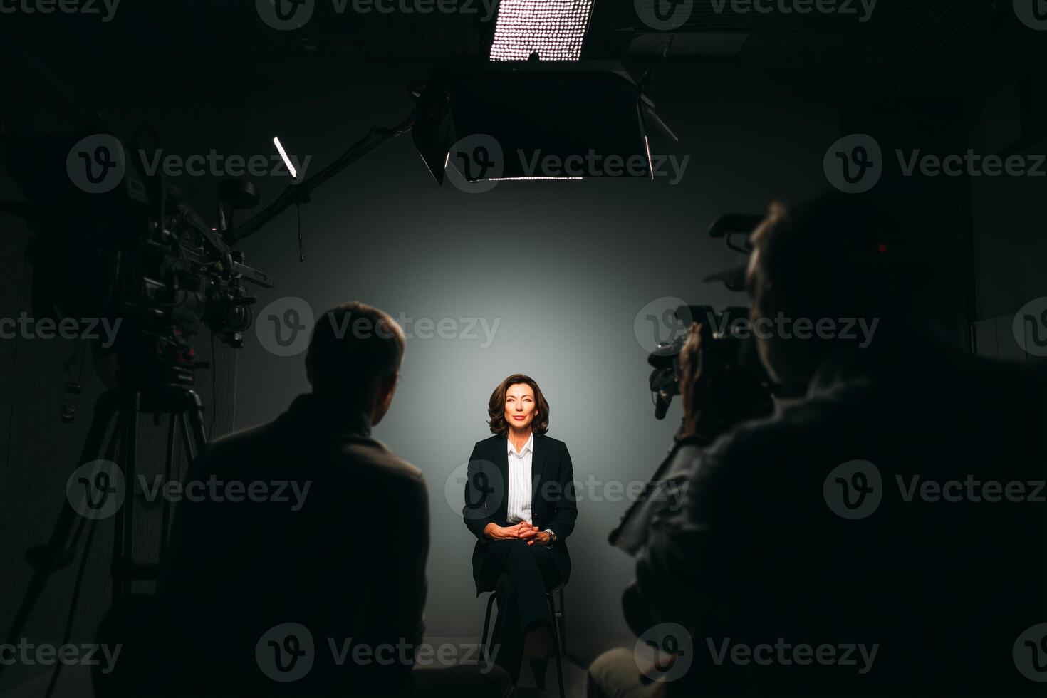 Professional interview setup with a woman speaking in front of cameras in a dimly lit studio photo