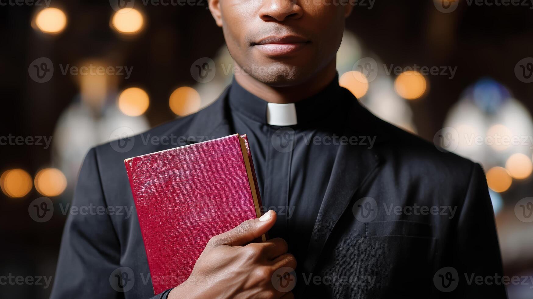 Clergy member holds a scripture book while standing in a dimly lit church during a worship service photo