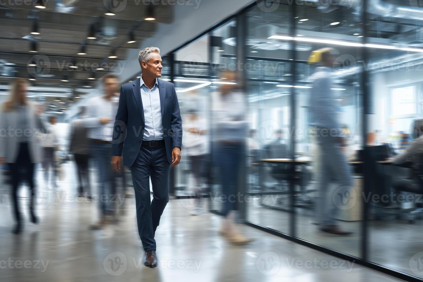 Business professional walking through a modern office filled with busy colleagues during a workday photo