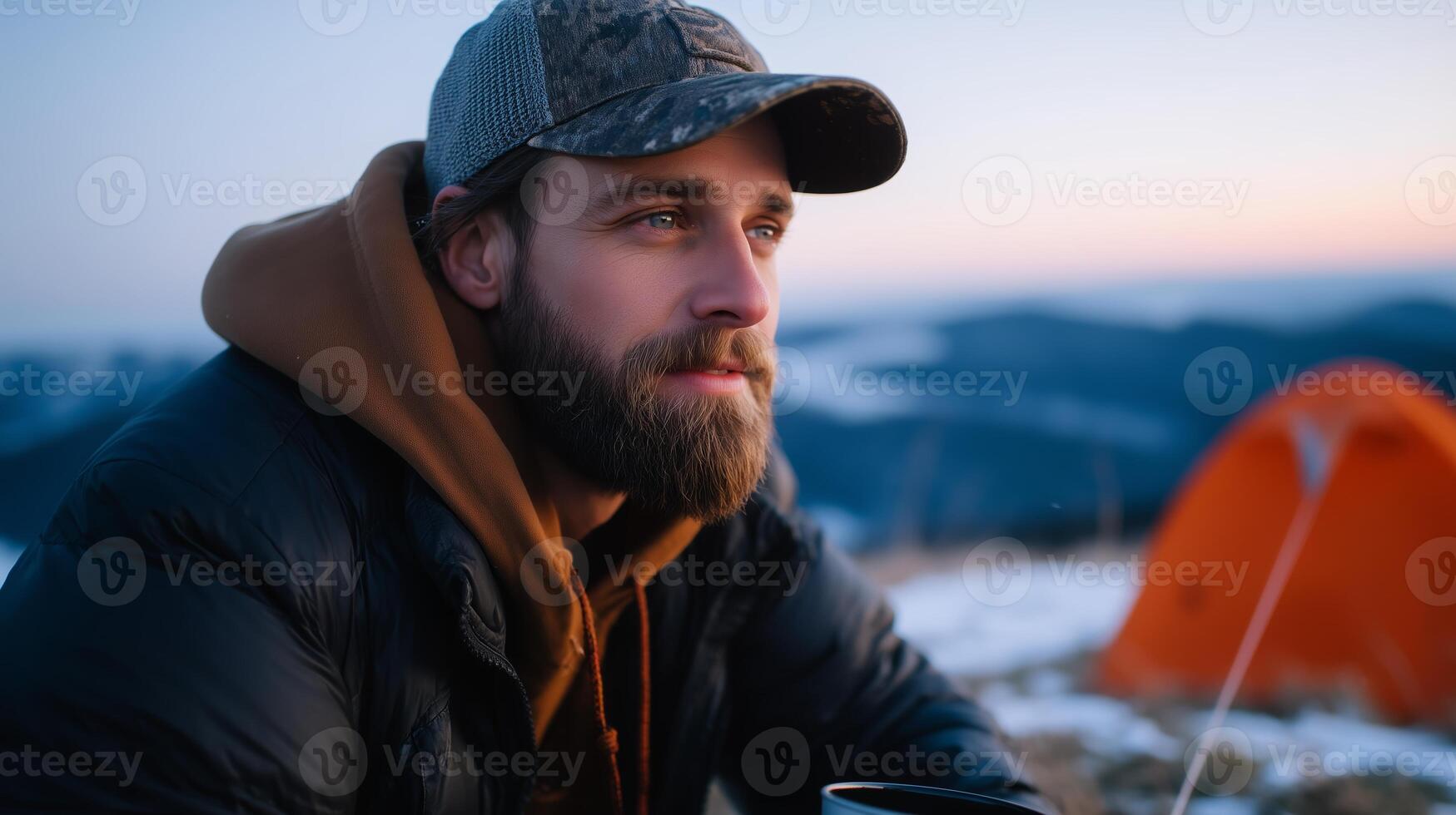 Outdoor adventure at sunset with a man enjoying a hot drink near a tent in the mountains photo