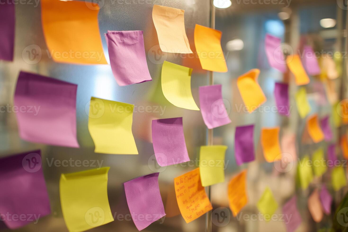 Colorful sticky notes on a glass wall in an office workspace during the day photo