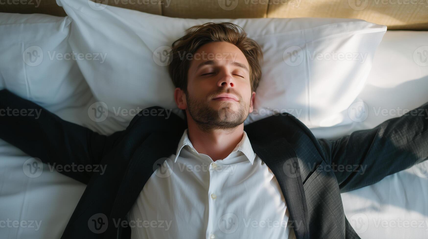 Professional man relaxing on a hotel bed with arms outstretched during a business trip in the afternoon photo