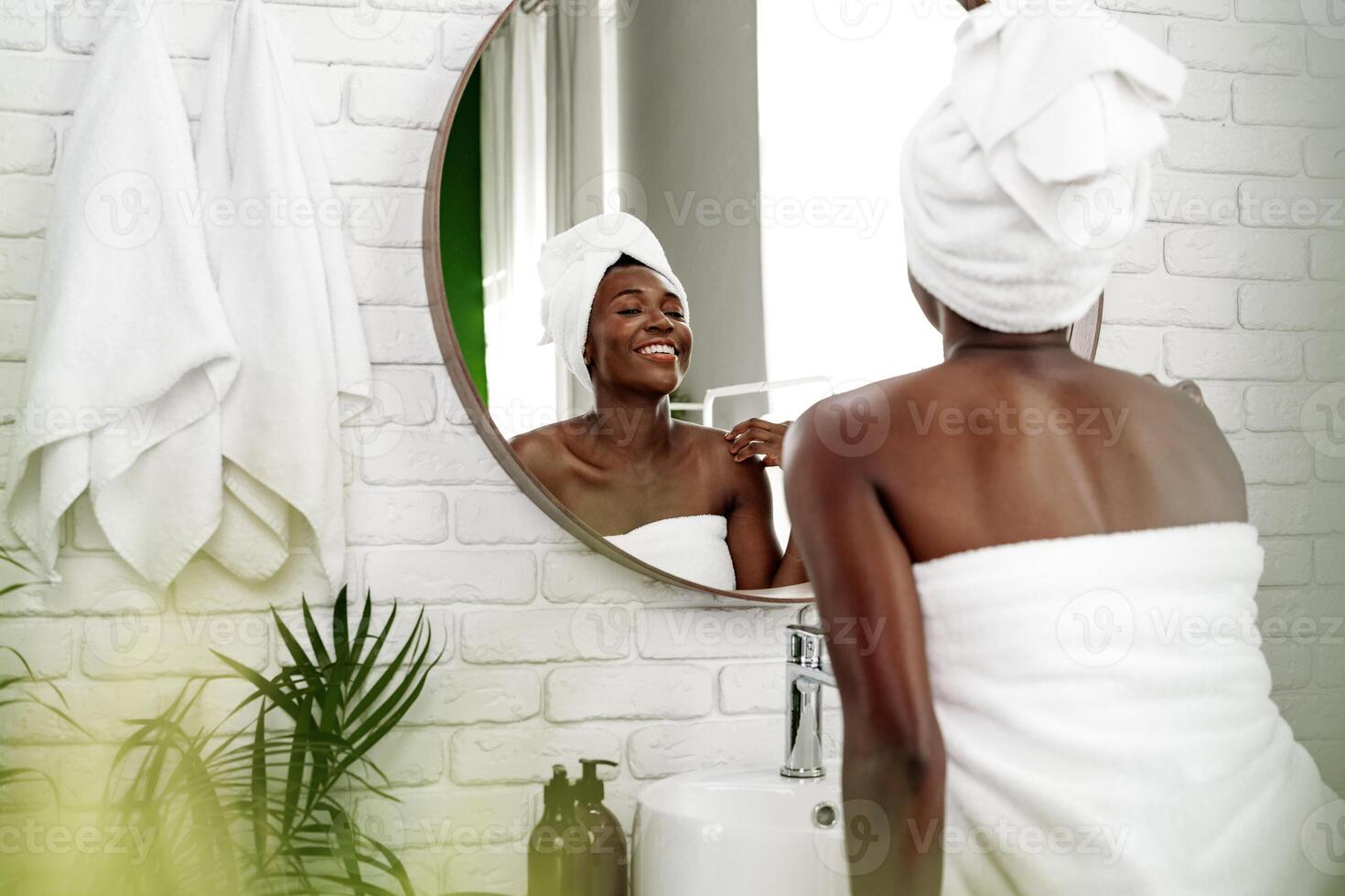Woman enjoying self-care routine while smiling in bathroom during daylight photo